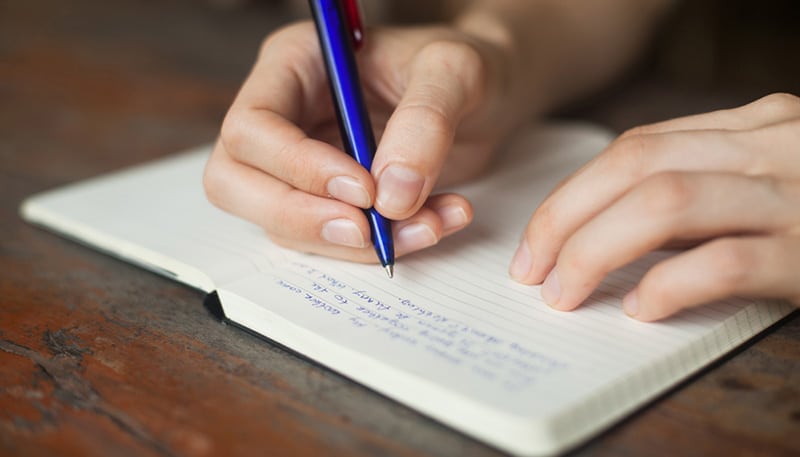 person writing in journal