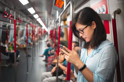 woman looking at cell phone on subway
